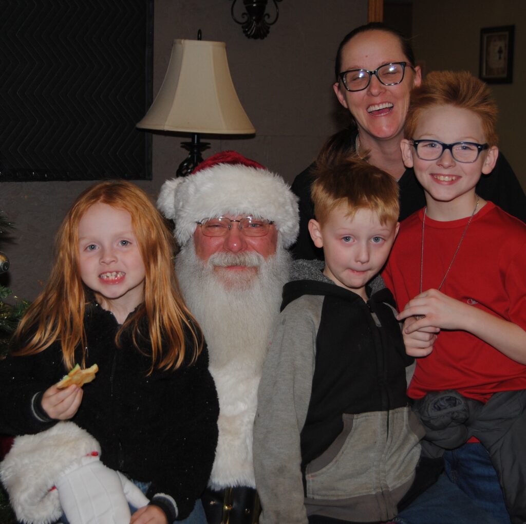 Santa Tom posing with a family during a Christmas event