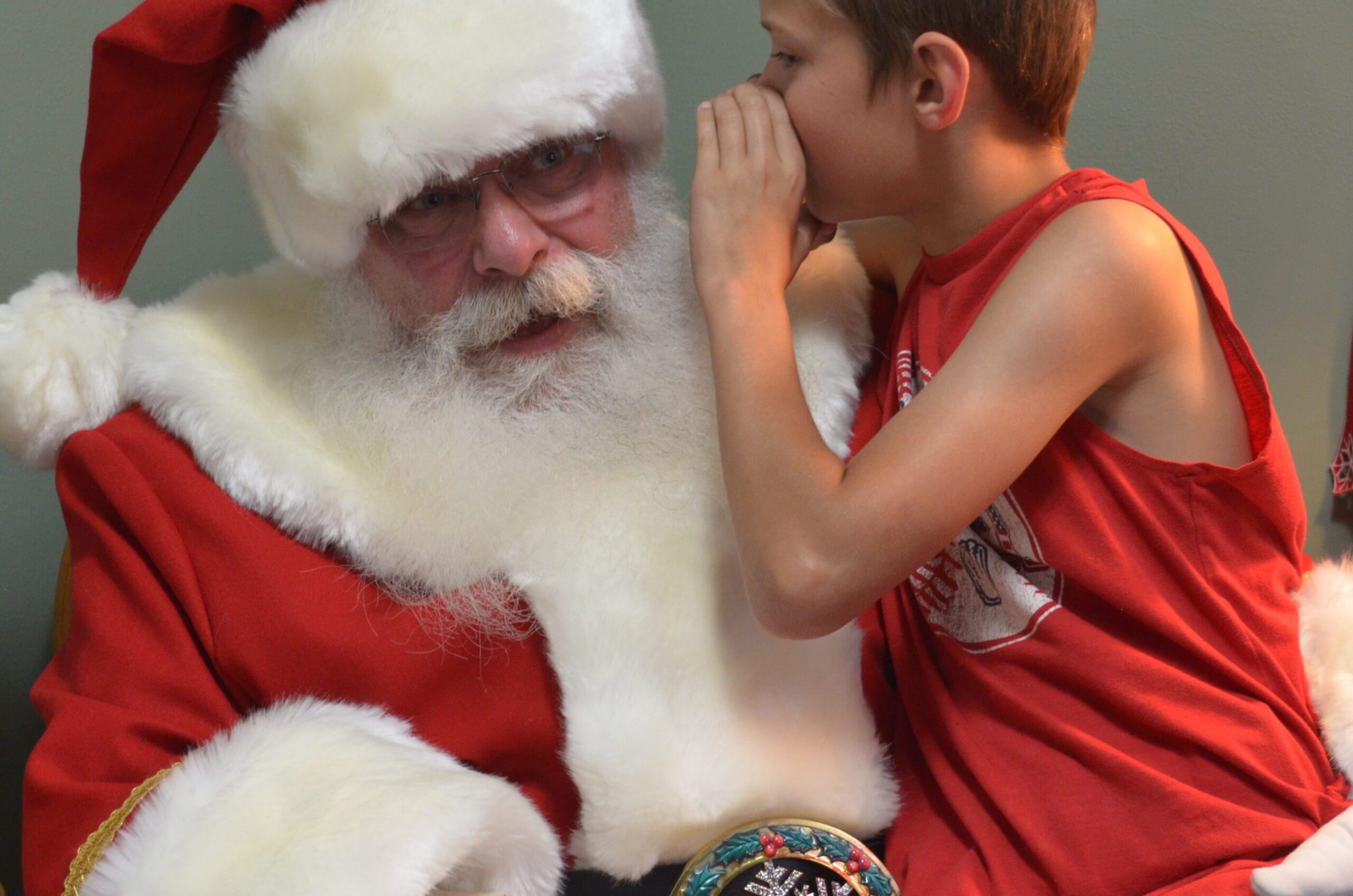 Boy whispering secrets into Santa Tom's ear