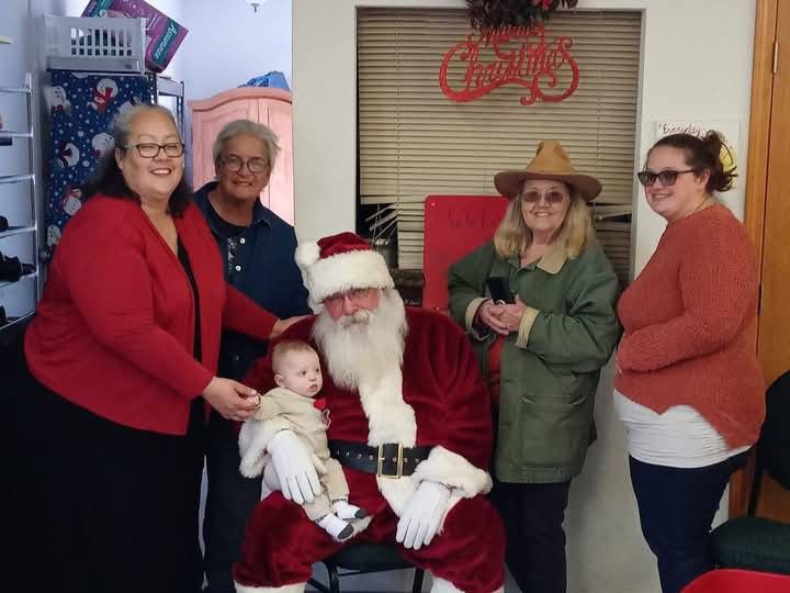 Santa Tom posing with guests and a young child during a Christmas community event.