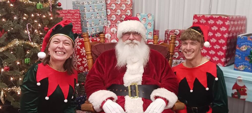 Santa Tom posing for photos with two elf helpers at a Central Missouri community event