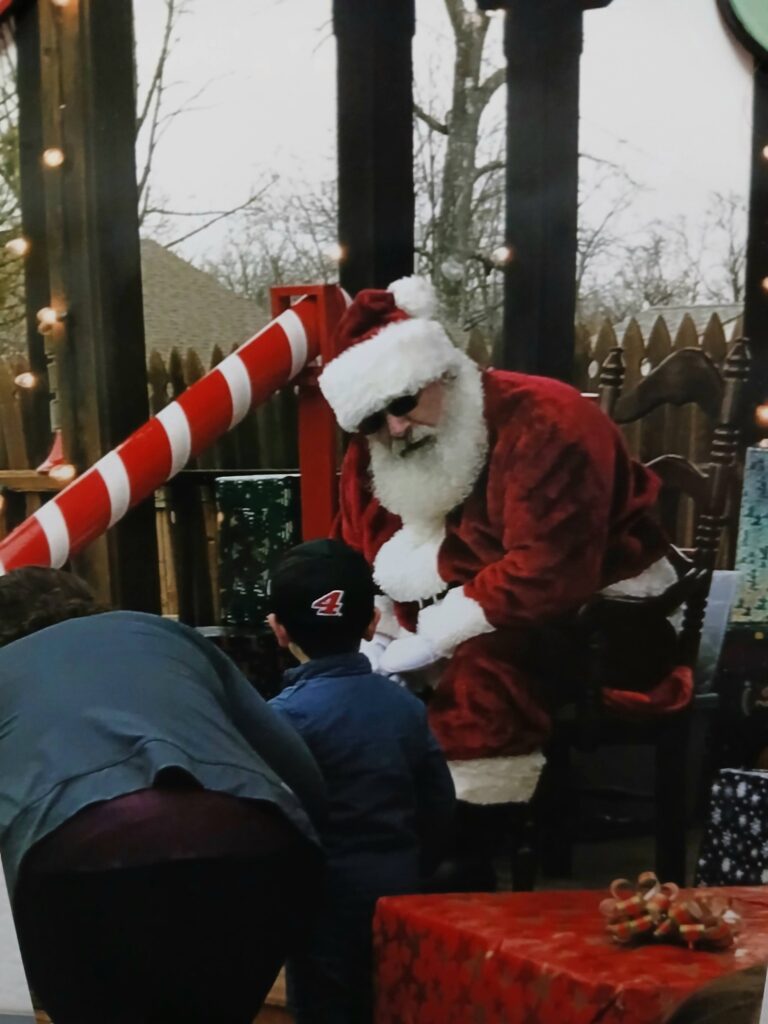 Santa Tom Listening to the Christmas Wishes of a Child at an Outdoor Christmas Event