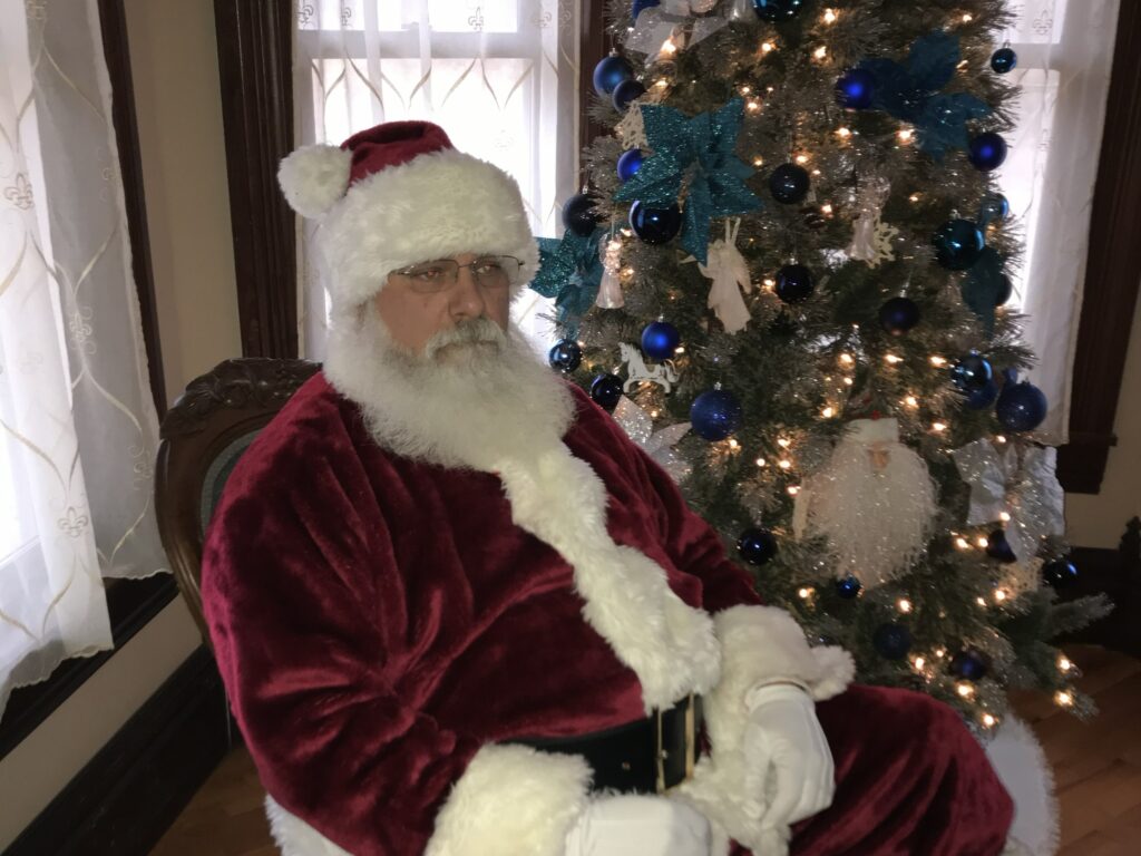 Santa Tom rocking next to a decorated tree