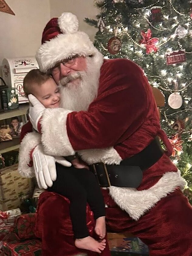 Santa Tom receiving and giving a big hug with an excited child at a family visit