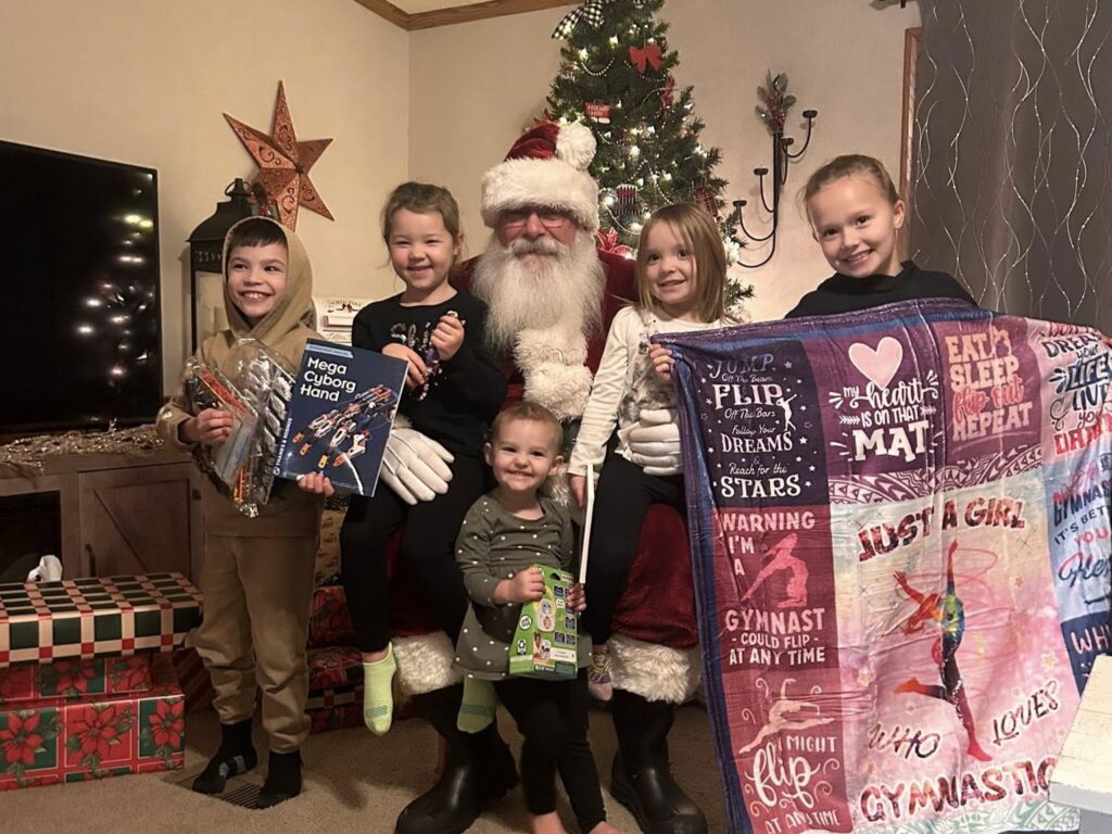 Santa Tom celebrating Christmas with children and their holiday gifts.