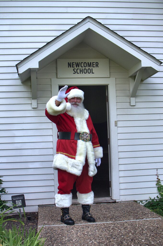 Santa Tom in a red Santa suit waving from the doorway of a white schoolhouse in Columbia, Missouri.