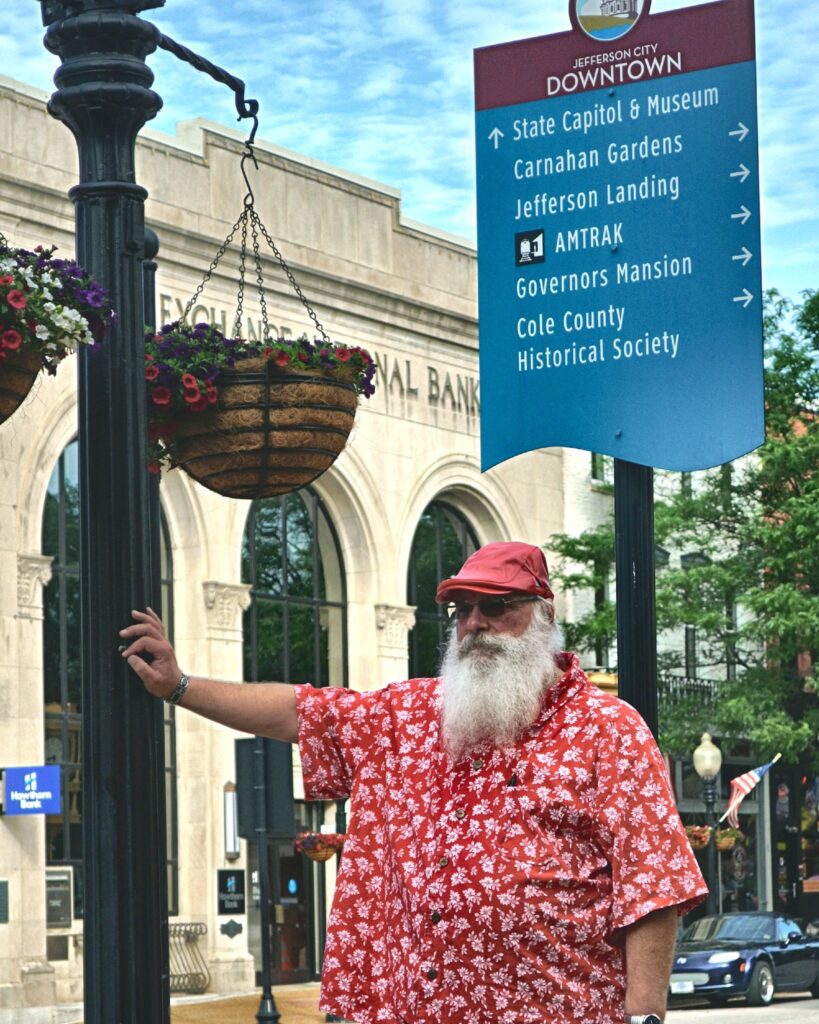 Santa Tom standing below a Jefferson City Downtown sign in Jefferson City, Missouri.