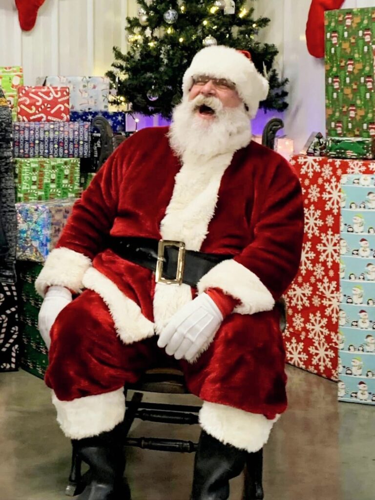 Santa Tom laughing warmly in a Christmas photo setting