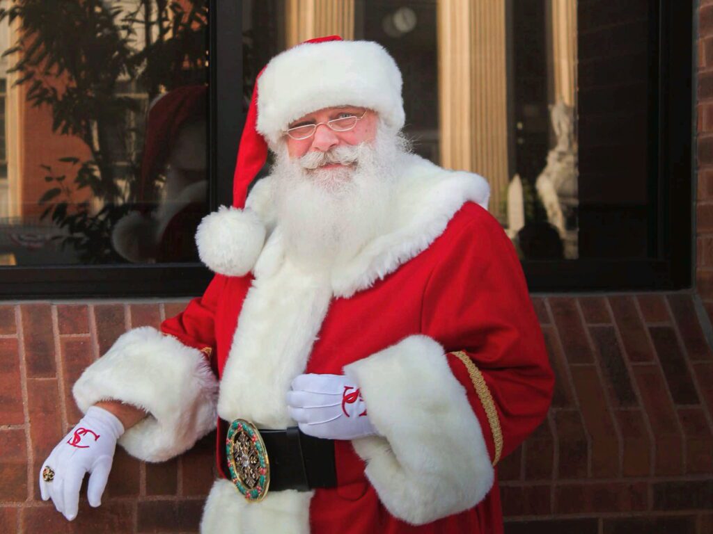 Santa Tom standing beside a brick storefront window in Fulton, Missouri.