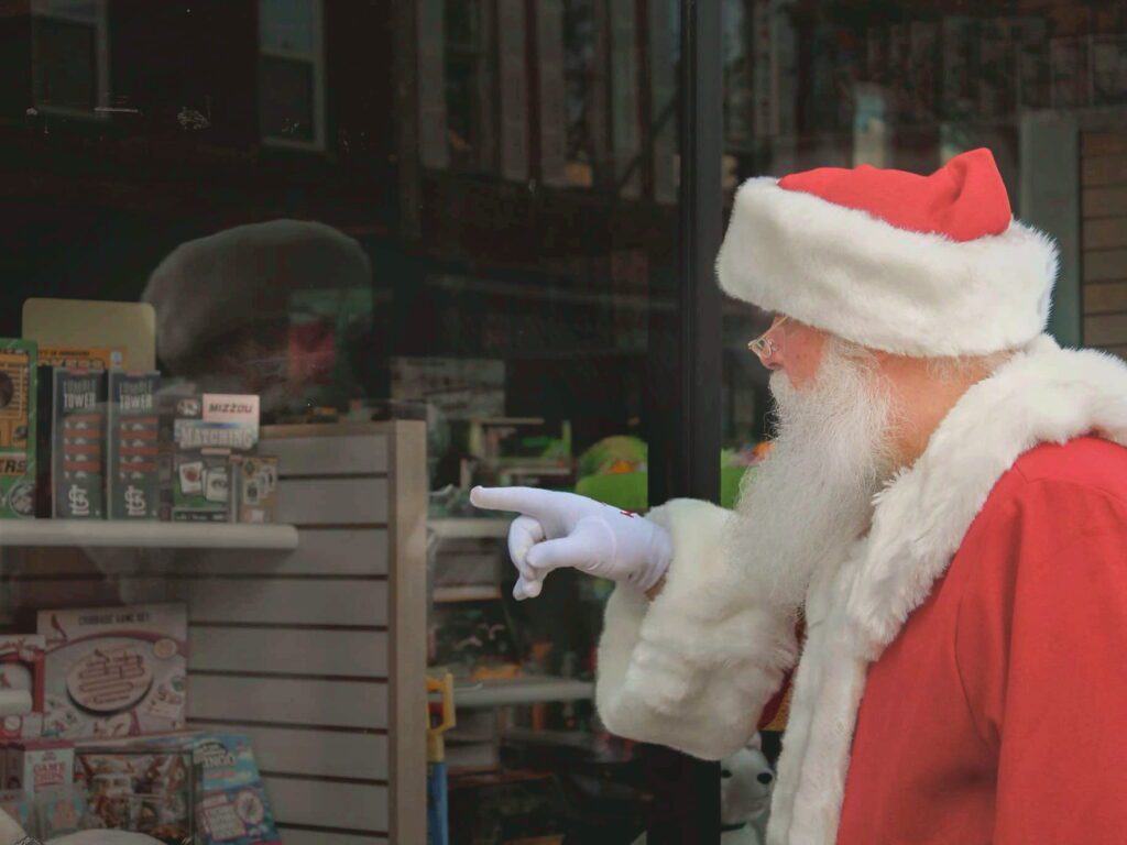 Santa Tom pointing into a downtown storefront window in Fulton, Missouri.